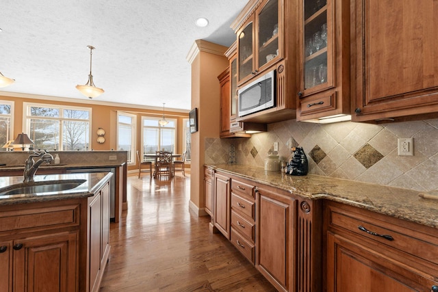 kitchen featuring decorative light fixtures, sink, crown molding, and light stone countertops