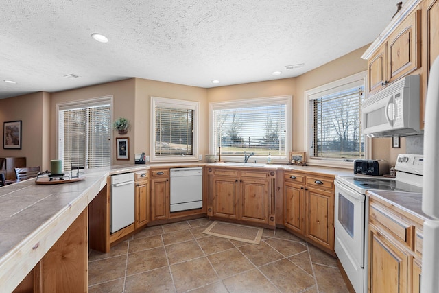 kitchen featuring tile countertops, white appliances, tile patterned flooring, a textured ceiling, and sink