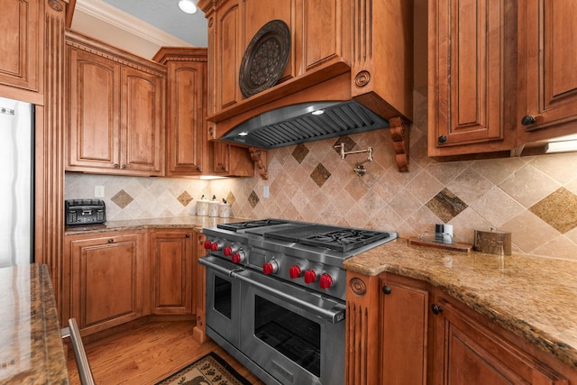 kitchen featuring decorative backsplash, light stone countertops, appliances with stainless steel finishes, and crown molding