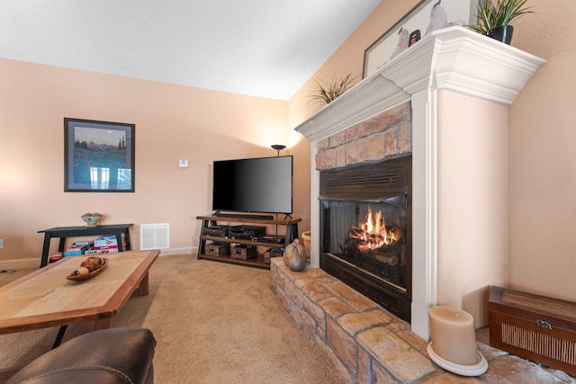 living room with light carpet, vaulted ceiling, and a stone fireplace