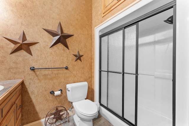 bathroom featuring toilet, a shower with shower door, and vanity