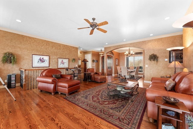 living room featuring wood-type flooring, ceiling fan with notable chandelier, and crown molding