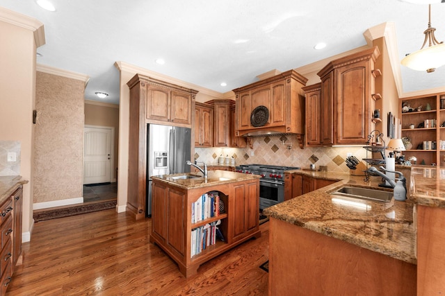 kitchen with pendant lighting, stainless steel appliances, an island with sink, sink, and crown molding