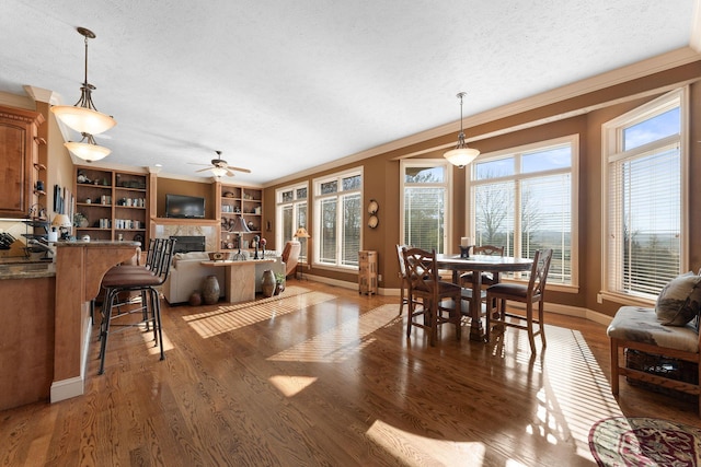 dining area featuring a healthy amount of sunlight, a fireplace, crown molding, and dark hardwood / wood-style floors