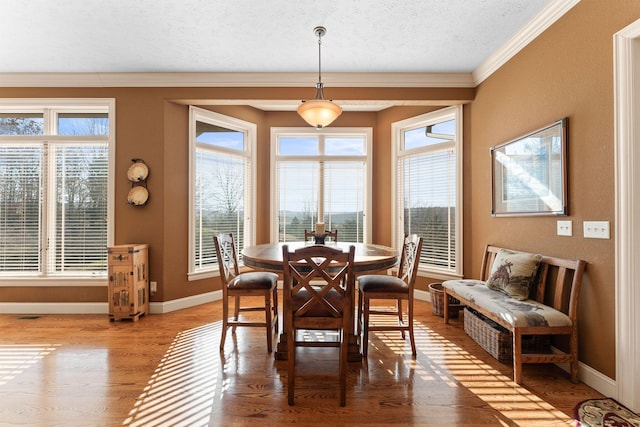 dining room with wood-type flooring, a textured ceiling, and ornamental molding