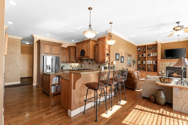 kitchen with hardwood / wood-style floors, stainless steel fridge with ice dispenser, light stone counters, crown molding, and a breakfast bar area