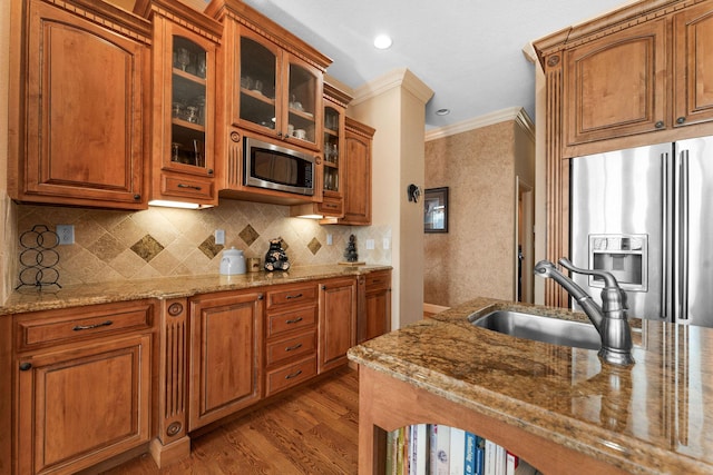 kitchen featuring appliances with stainless steel finishes, tasteful backsplash, sink, light stone counters, and crown molding