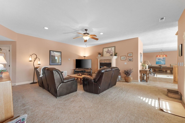 carpeted living room with ceiling fan and a fireplace