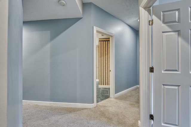 hall with light colored carpet and a textured ceiling