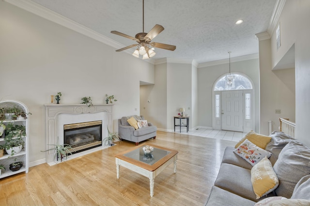 living room with ceiling fan, crown molding, light hardwood / wood-style floors, and a textured ceiling