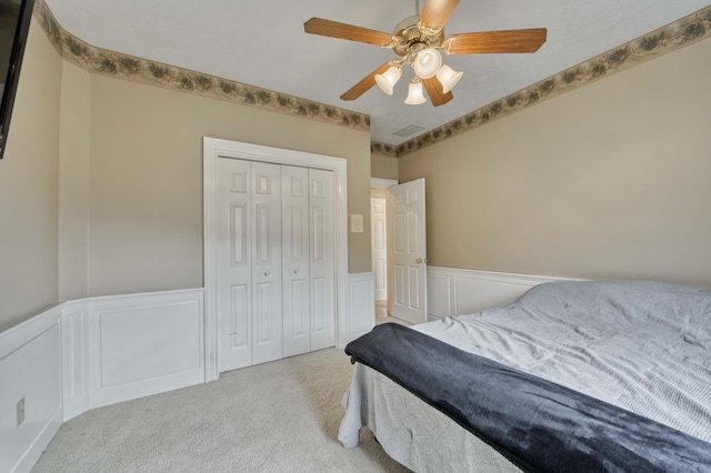 bedroom with ceiling fan, a closet, and light carpet