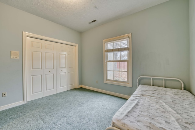 carpeted bedroom featuring a closet and a textured ceiling