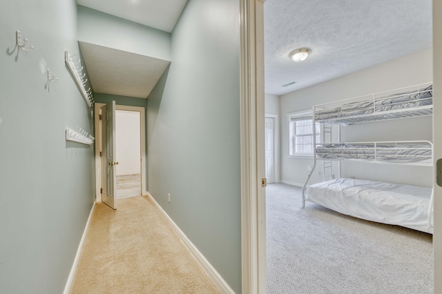 hallway featuring a textured ceiling and light colored carpet