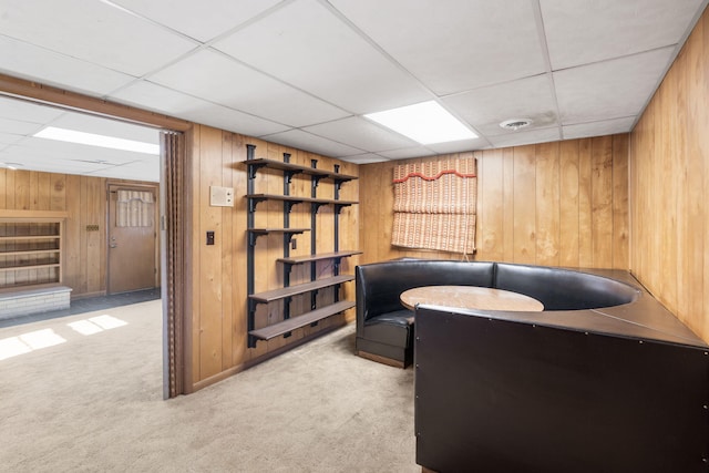 office area with a paneled ceiling, light colored carpet, and wooden walls