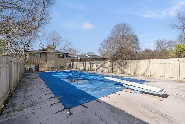 view of swimming pool with a diving board and a patio area