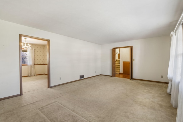 carpeted spare room featuring a chandelier