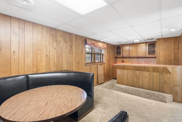 bar with a paneled ceiling, light colored carpet, and wooden walls