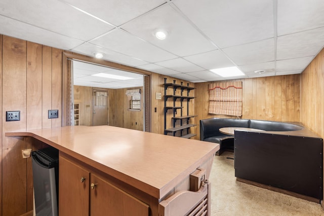 kitchen featuring a paneled ceiling, wood walls, light colored carpet, and fridge