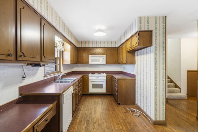 kitchen featuring light wood-type flooring, white appliances, and sink