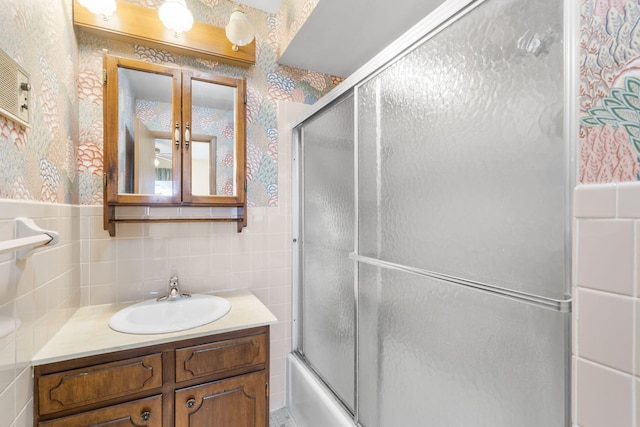 bathroom with vanity, enclosed tub / shower combo, and tile walls