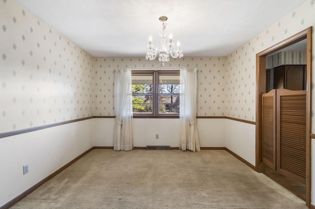 spare room featuring a notable chandelier and light colored carpet