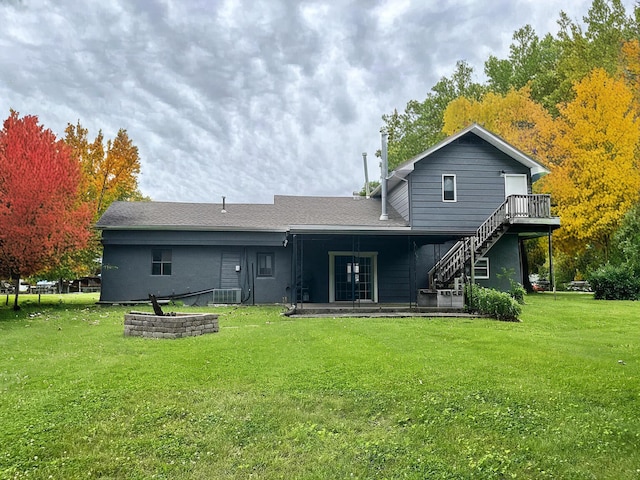 rear view of property featuring a lawn and stairs