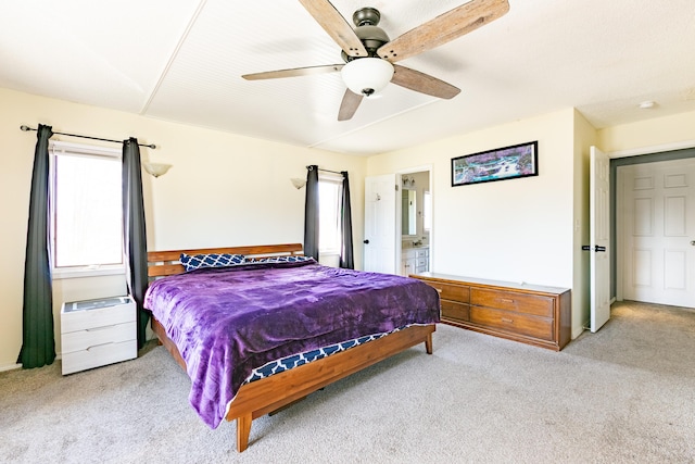 bedroom with light colored carpet, a ceiling fan, and connected bathroom