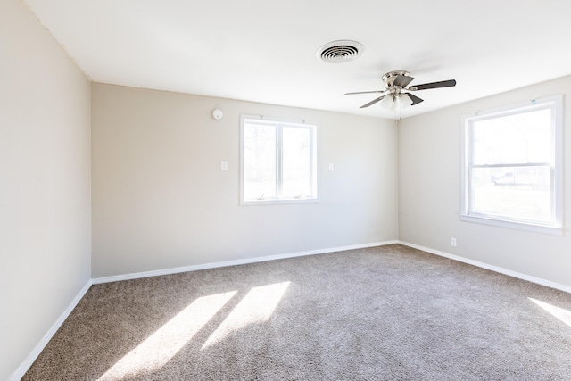 carpeted spare room with visible vents, baseboards, and a ceiling fan