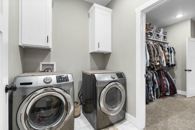 laundry area featuring washer and clothes dryer, light colored carpet, and cabinets