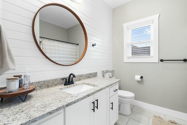 bathroom featuring tile patterned floors, vanity, toilet, and wooden walls