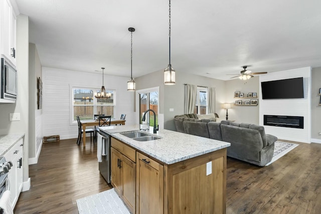 kitchen featuring light stone countertops, sink, hanging light fixtures, an island with sink, and white cabinets