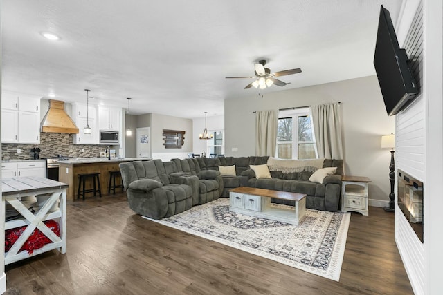 living room featuring dark hardwood / wood-style flooring, ceiling fan with notable chandelier, and sink