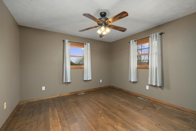 unfurnished room with a textured ceiling, dark hardwood / wood-style flooring, ceiling fan, and a healthy amount of sunlight