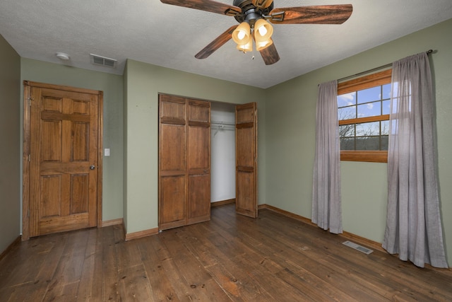 unfurnished bedroom featuring ceiling fan, dark hardwood / wood-style flooring, a textured ceiling, and a closet