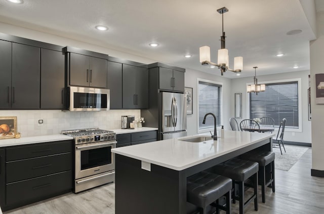 kitchen with appliances with stainless steel finishes, a breakfast bar, sink, decorative light fixtures, and a notable chandelier