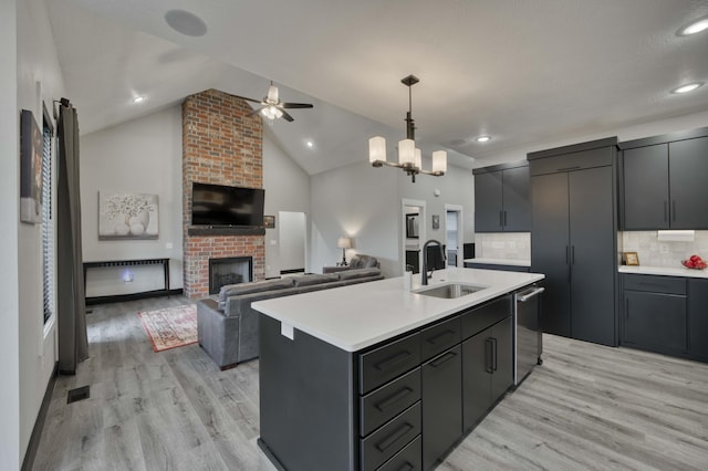 kitchen featuring decorative backsplash, an island with sink, hanging light fixtures, and lofted ceiling