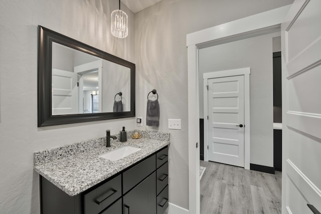 bathroom featuring vanity, wood-type flooring, and an inviting chandelier