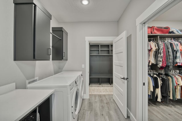 laundry area featuring cabinets, a textured ceiling, light hardwood / wood-style flooring, and washing machine and clothes dryer