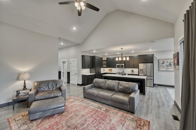 living room with ceiling fan, sink, high vaulted ceiling, and light hardwood / wood-style floors