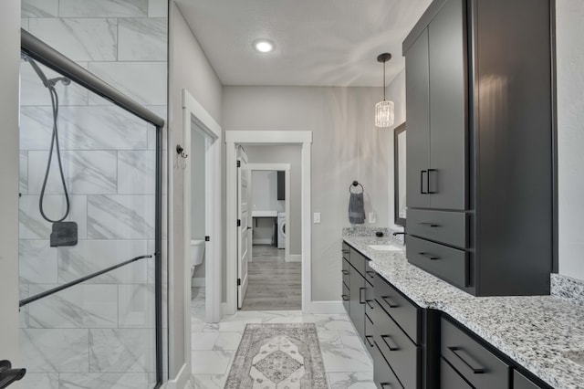 bathroom with walk in shower, washer / dryer, an inviting chandelier, toilet, and vanity