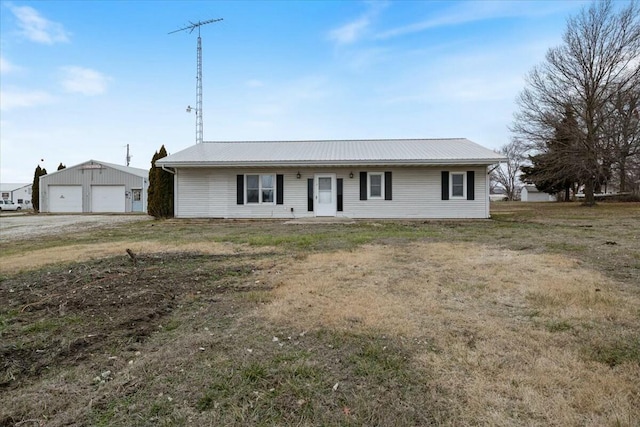 single story home featuring an outbuilding, a garage, and a front lawn