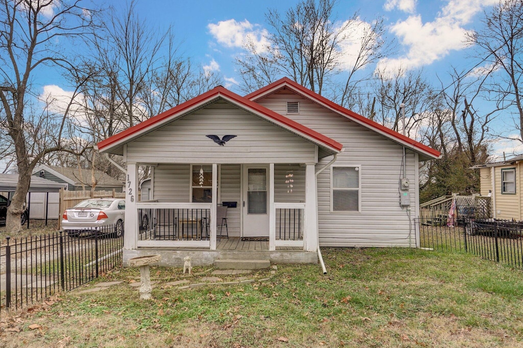 bungalow-style home featuring covered porch and a front yard