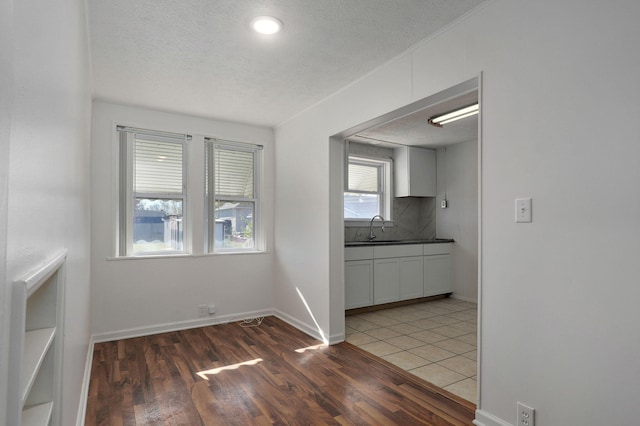 unfurnished dining area with a textured ceiling, sink, and dark wood-type flooring