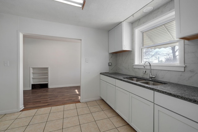 kitchen with white cabinetry, sink, light tile patterned flooring, and a textured ceiling