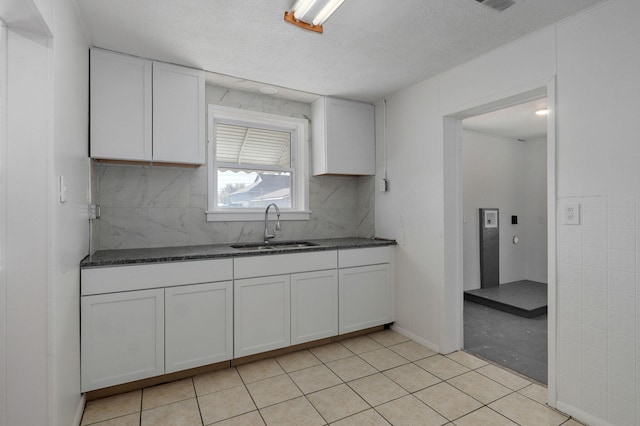 kitchen featuring white cabinets, a textured ceiling, light tile patterned flooring, and sink