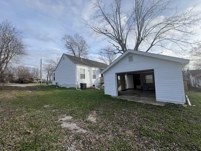 back of house featuring a lawn, a garage, central air condition unit, and an outbuilding