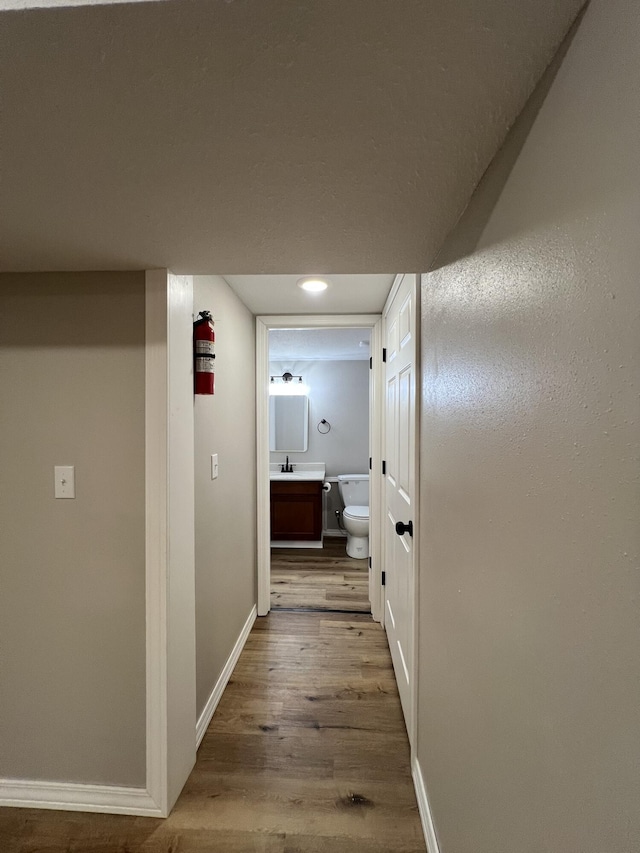 corridor with hardwood / wood-style flooring and sink