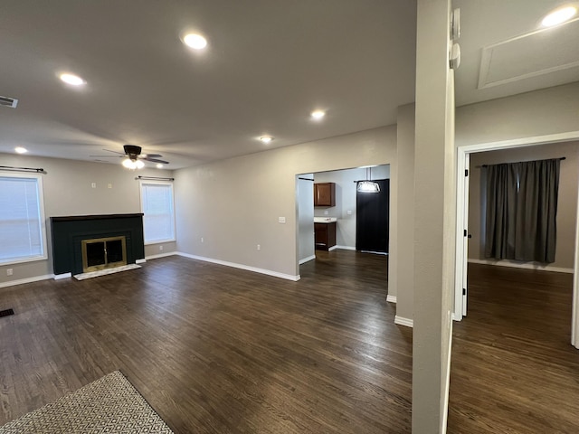 unfurnished living room featuring ceiling fan and dark wood-type flooring