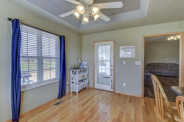 entryway featuring ceiling fan, light hardwood / wood-style floors, and a raised ceiling