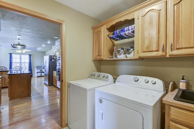 laundry room with ceiling fan, washing machine and dryer, light wood-type flooring, and cabinets